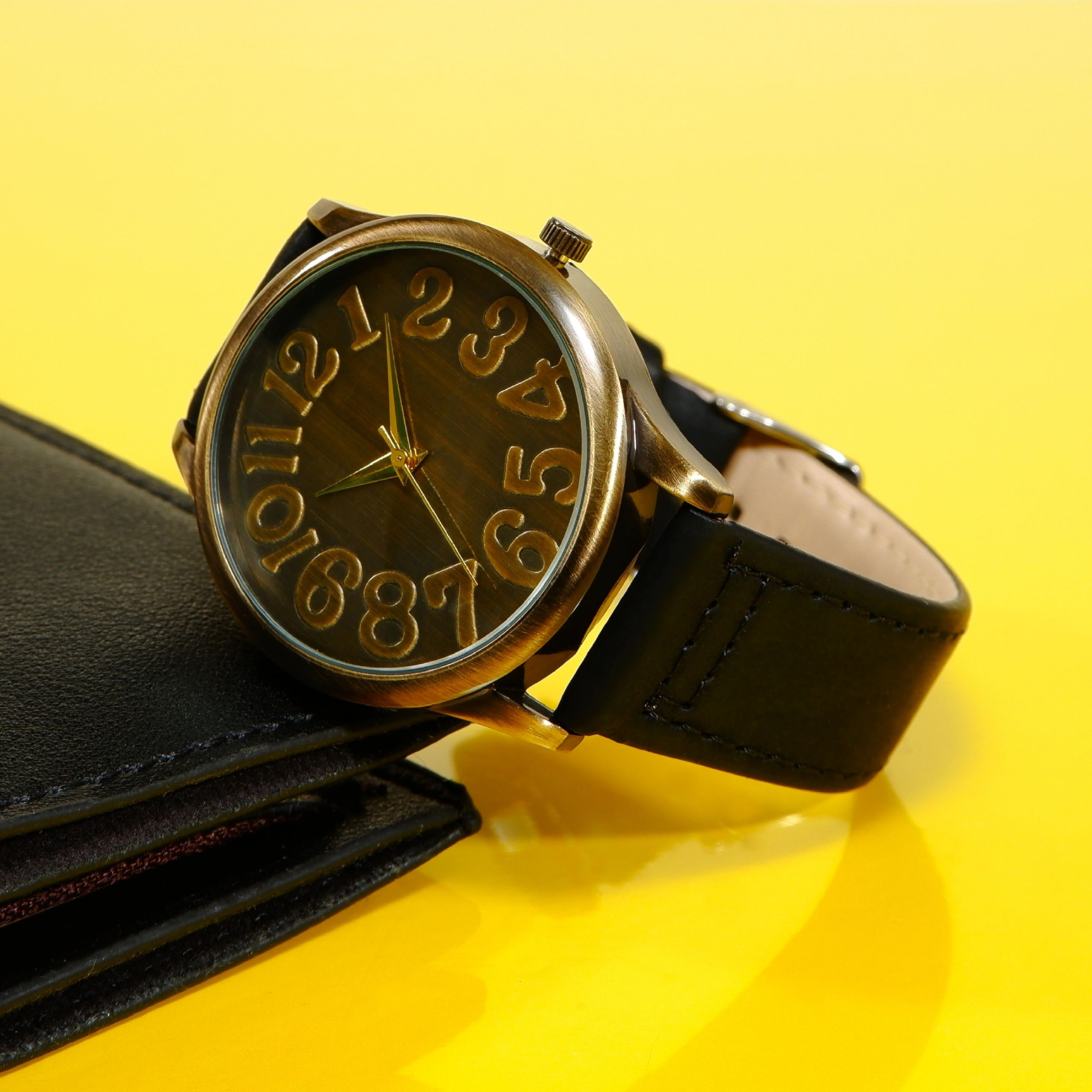 Elegant wrist watch with black leather strap displayed on yellow background closeup shot